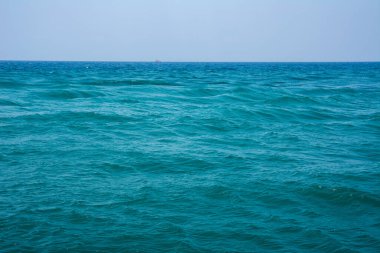 Beautiful sea with turquoise colored waves. Sea waves in the open sea, a boat can be seen on the horizon.