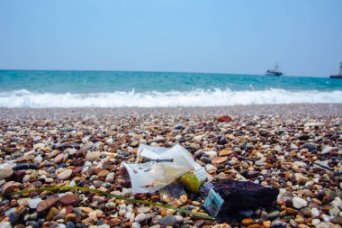 Garbage on the sea beach. A man-made garbage in the sea: plastic bottles, glasses and other plastic. Photo shows the problems of the environment due to pollution of the Earth with plastic waste.