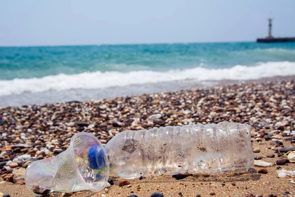 Garbage on the sea beach. A man-made garbage in the sea: plastic bottles, glasses and other plastic. Photo shows the problems of the environment due to pollution of the Earth with plastic waste.