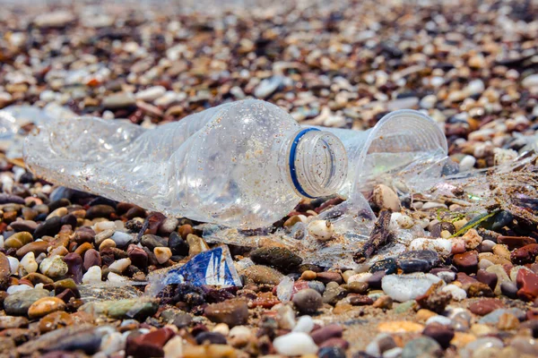 Garbage on the sea beach. A man-made garbage in the sea: plastic bottles, glasses and other plastic. Photo shows the problems of the environment due to pollution of the Earth with plastic waste.