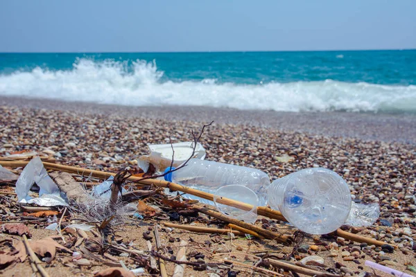 Garbage on the sea beach. A man-made garbage in the sea: plastic bottles, glasses and other plastic. Photo shows the problems of the environment due to pollution of the Earth with plastic waste.