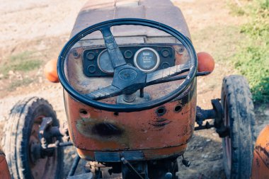 Açık taksisi olan eski kırmızı bir traktör. Taksisiz kırsal bir traktörün fotoğrafı. Traktörün ön tarafına yakın çekim: radyatör, farlar.