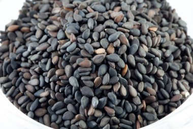 Beyaz arkaplanda izole edilmiş siyah susam tohumları yığını