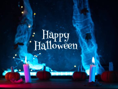 Mutlu Cadılar Bayramı. Tebrikler, koyu mavi arka plan, yanan mumlar ve küçük balkabakları.