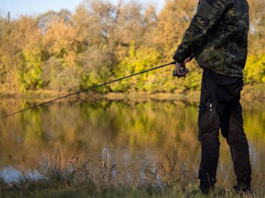 Genç bir adam elinde olta olan bir balıkçıdır. Sonbahar balıkçılığı, açık hava aktiviteleri ve hobiler. Arka görünüm, boşluğu kopyala