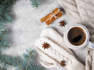 Soğuk mevsimin kompozisyonu. Süveter giymiş kahve kupası beyaz masanın üzerinde örgü örülmüş eşarp, tarçın, anason, ağaç dalları ve fotokopi dairesi