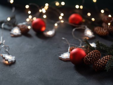 Noel arkaplanı. Koyu arkaplanlı Noel ağacı dalları, kırmızı toplar, çelenk ve kopyalama alanı