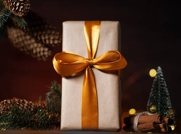 金リボンでクラフト紙に包まれたクリスマスプレゼント コーンとクリスマスツリーの枝 クリスマスの夜 — ストック写真