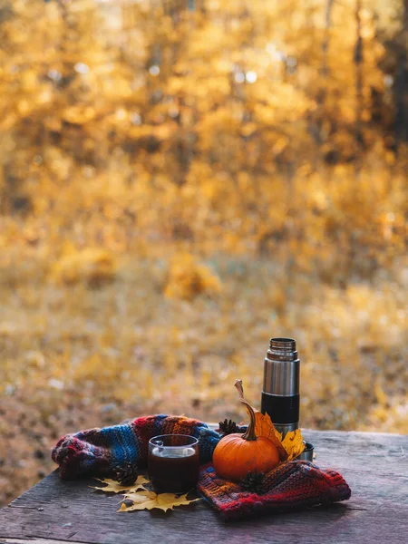 Outdoor recreation in October. Drink hot coffee in a Cup on a wooden table against the background of a colorful autumn forest. Romance and enjoy life