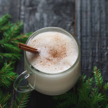 Noel içkisi, ağaç dalları olan ahşap masada yumurtalı nog.