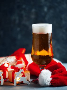 Noel Baba şapkasıyla koyu arkaplanda Noel birası kadehi.