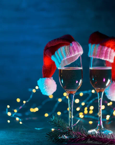 Dvě Sklenice Šampaňského Klobouku Santa Claus Modrém Dřevěném Pozadí Bokeh — Stock fotografie