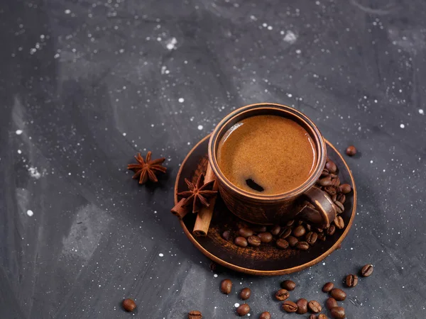 A cup of espresso coffee and roasted coffee beans on a black background, copy space
