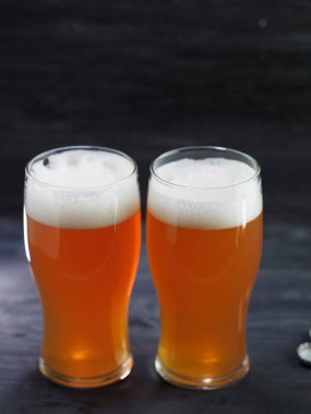 Koyu ahşap arka planda iki bardak IPA birası. Filtresiz bira