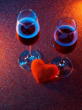 Sevgililer günü kartı. Parlak kırmızı bir arka planda iki bardak köpüklü şarap ve kırmızı bir kalp. Boşluk seçici odağı kopyala