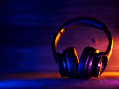 Kablosuz, modaya uygun kulaklıklar. Arka planda koyu bir fon var.