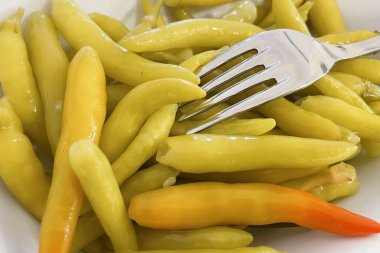 Beyaz bir tabakta hazır biber turşusu.