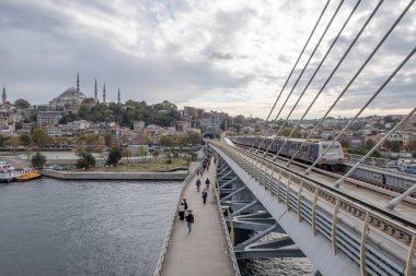 Golden Horn, istanbul, Türkiye. Sonbahar mevsiminde Golden Horn metro köprüsünün manzarası ve gezginler ve turistler için bulutlu bir gün..