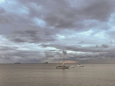 Sahilde tekneler ve fırtına bulutları