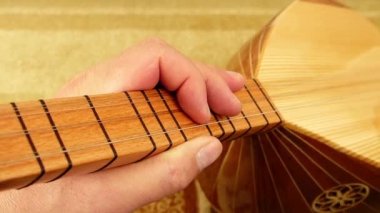 Bir müzisyen elinde saz, Türk enstrümanları, yakın plan baglama, saz tutuyor.