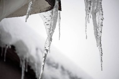 Çatıda buz saçakları, kar yağıyor, sert bir kış.,