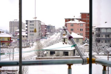 Bir evin, karın ve şehrin cam balkonundan kış manzarası. Kar yağarken bir şehir.,
