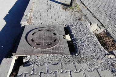 Bir kaldırım kapağı, demir lağım kapağı, yol kenarında güvenlik önlemleri alınmamış..