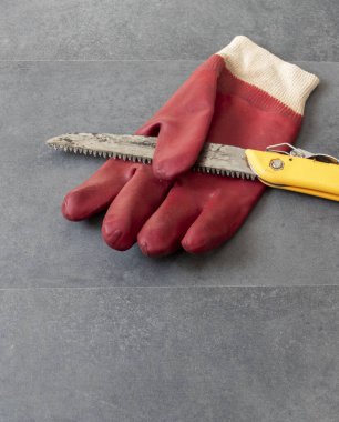 Atölye testeresi ve kalın iş eldivenlerinde çalışırken el yaralanmalarını önlemek için eldiven kullanıyor.-