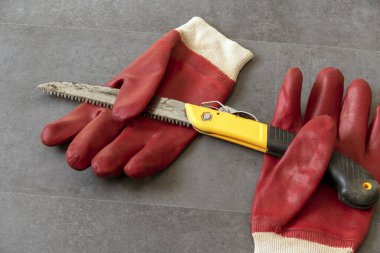 Atölye testeresi ve kalın iş eldivenlerinde çalışırken el yaralanmalarını önlemek için eldiven kullanıyor.-