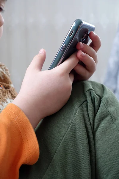 Akıllı telefonuyla oynayan bir çocuğun yakın plan el ve cep telefonunun görüntüsü.,