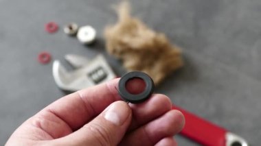 Bir muslukçunun elinde su mührü var-- Yerde, bir ingiliz anahtarı ve bir su tesisatı örtüsü var..