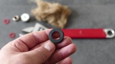 Bir muslukçunun elinde su mührü var-- Yerde, bir ingiliz anahtarı ve bir su tesisatı örtüsü var..