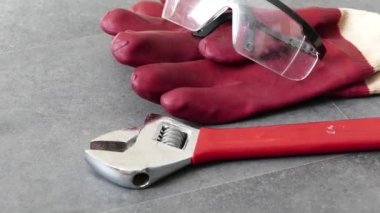 İş güvenliği için, eldivenlerle çalışmak gereklidir, bir ingiliz anahtarı, kalın plastik eldivenler yerde duruyordur.,