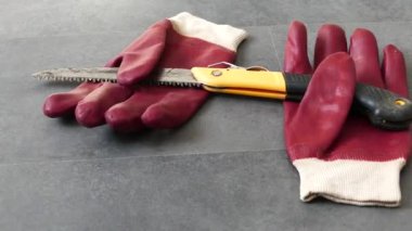 İş güvenliği için, eldivenlerle çalışmak gereklidir, bir el testeresi ve yerde kalın plastik eldivenler vardır.,