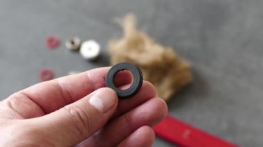 Bir muslukçunun elinde su mührü var-- Yerde, bir ingiliz anahtarı ve bir su tesisatı örtüsü var..