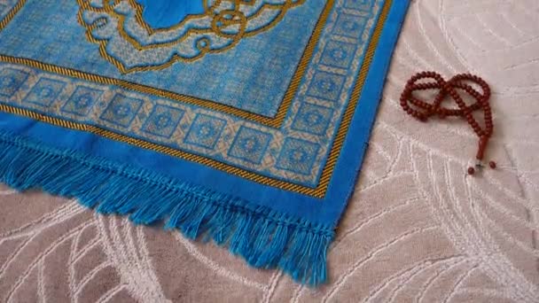 穆斯林和他的念珠旁边的房子里的一块蓝色的祈祷毯 — 图库视频影像