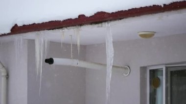Çatıda buz saçakları, kar yağıyor, sert bir kış.,