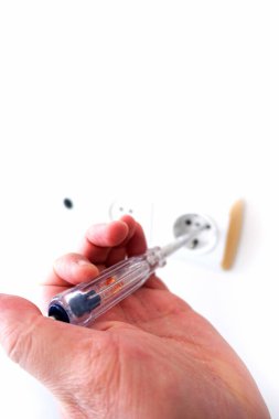 Elektrik prizindeki elektriği elektrik kontrol kalemiyle ölçen bir elektrikçi.,