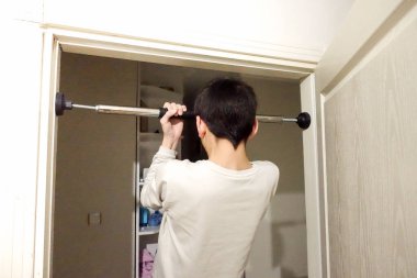 Evin kapısına barfiks çeken genç bir adam var.,