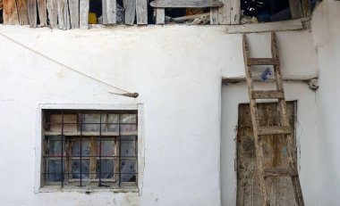 The old village house and the wooden ladder placed on its roof,