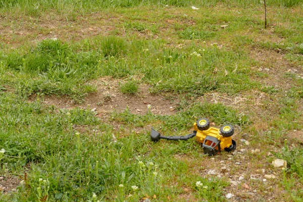 草の上に残されたプラスチック製の建設機械のおもちゃ地面に残されたおもちゃ — ストック写真