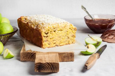 Elmalı ve hindistancevizli pasta ahşap kesim tahtası ve vazoda elmalar