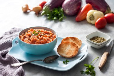 Mavi kasede patlıcan havyarı ve arka planda taze sebzeler..