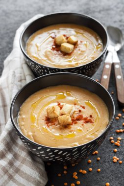 Kırmızı biberli mercimek kremalı çorba ve koyu arkaplanda siyah seramik kaseler. Boşluğu kopyala