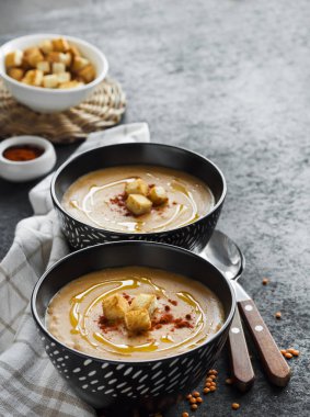Kırmızı biberli mercimek kremalı çorba ve koyu arkaplanda siyah seramik kaseler. Boşluğu kopyala