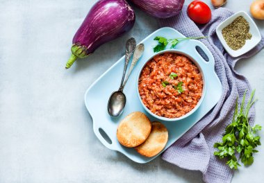 Mavi kasede patlıcan havyarı ve arka planda taze sebzeler. Düz konum, üst görünüm, kopyalama alanı