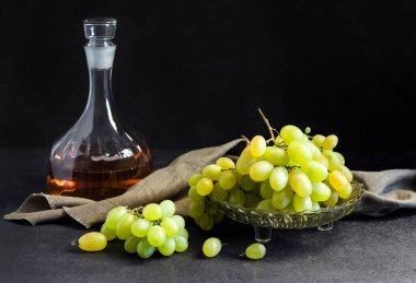 Meyve kasesinde taze üzümler ve siyah arka planda üzüm suyu ile sürahiler.