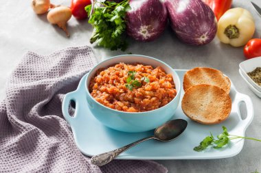 Mavi kasede patlıcan havyarı ve arka planda taze sebzeler..