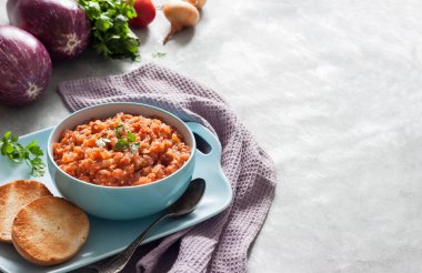 Mavi kasede patlıcan havyarı ve arka planda taze sebzeler. Boşluğu kopyala