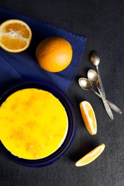 Kremalı turuncu pasta ve koyu arkaplanda turuncu jöle. Düz yatış, üst görünüm.